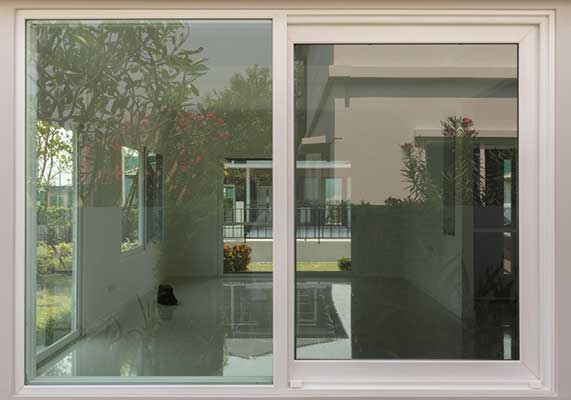 Modern home exterior featuring a white-framed sliding window with clear glass reflecting indoor and outdoor spaces, highlighting clean design, natural light, and professional Window Replacement Alpharetta services for energy-efficient living.