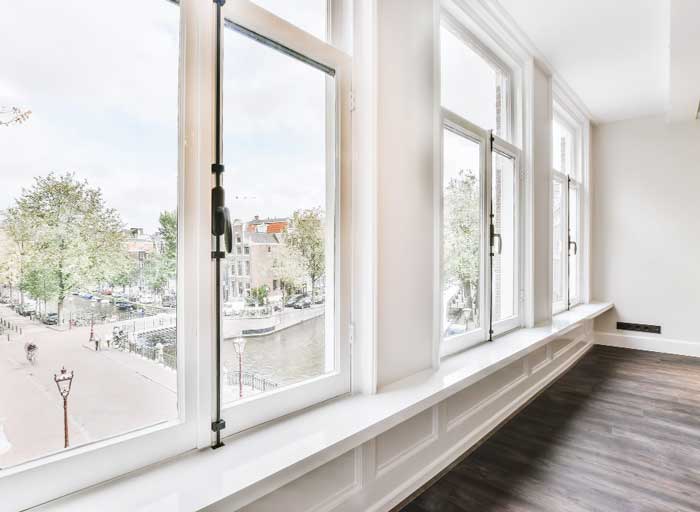 Bright interior space with a row of white-framed windows overlooking a city street and canal, enhancing natural light and views while showcasing modern design and professional Window Replacement Alpharetta services for energy-efficient homes.