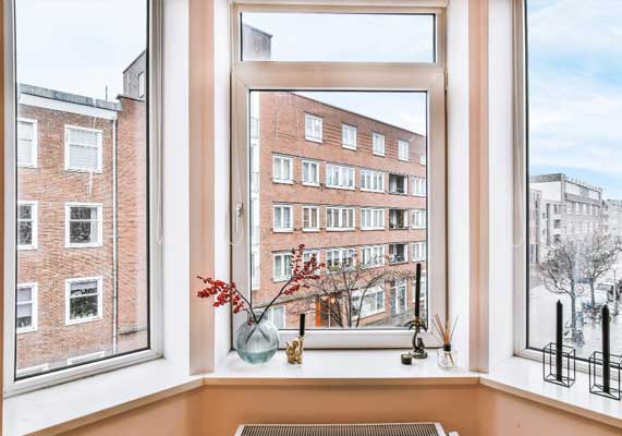 Interior bay window with white frames and decorative accents overlooking brick apartment buildings, enhancing natural light and city views while showcasing professional Window Replacement Atlanta services for modern, energy-efficient homes.