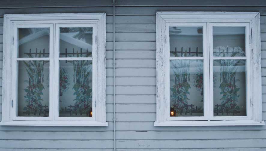 Gray home exterior featuring two white-framed casement windows with decorative curtains, showcasing classic charm, symmetrical design, and professionally installed Casement Windows Atlanta for improved ventilation and energy efficiency.