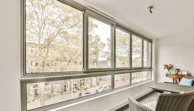 Bright interior sunroom with a row of large casement windows overlooking a tree-lined street, allowing maximum natural light and airflow while showcasing modern design and professionally installed Casement Windows Atlanta.