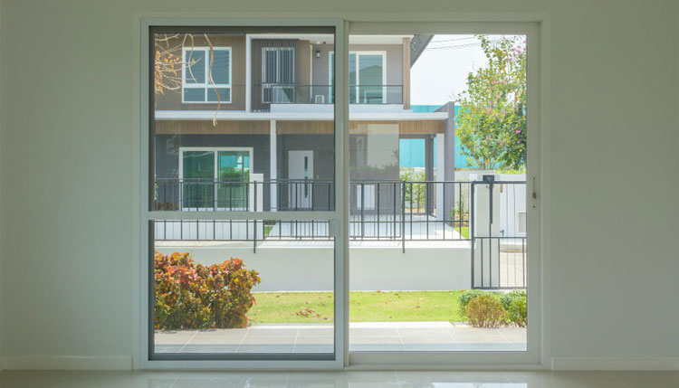 Interior view of large white-framed windows overlooking a modern residential building and landscaped yard, bringing in natural light and showcasing clean design with professionally installed Double Hung Windows Atlanta for energy efficiency and comfort.