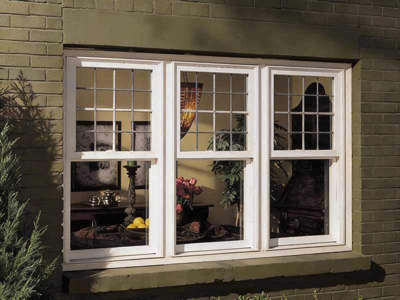 Couple sitting at a table by a large white-framed window enjoying coffee and conversation in a bright modern interior, highlighting natural light, comfort, and professional Window Replacement Atlanta services for stylish, energy-efficient spaces.