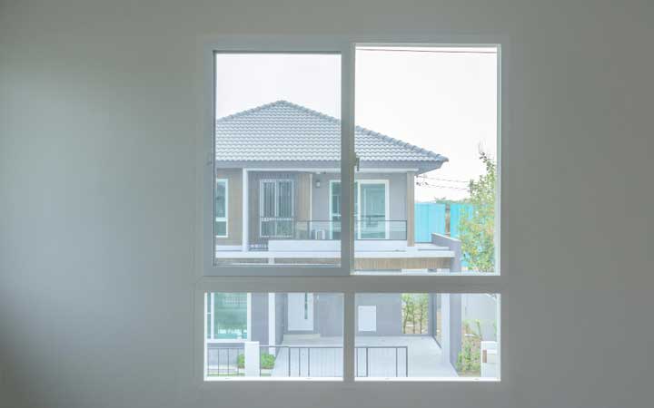 Minimalist building exterior with a blue-framed window featuring closed blinds, showcasing clean modern architecture, privacy, and professional Window Replacement Atlanta services for durability and energy efficiency.