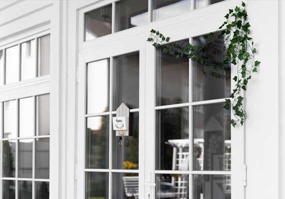 White home exterior with large grid-style windows and decorative greenery, showcasing classic design, natural light, and professional Window Replacement Marietta services for enhanced beauty and energy efficiency.