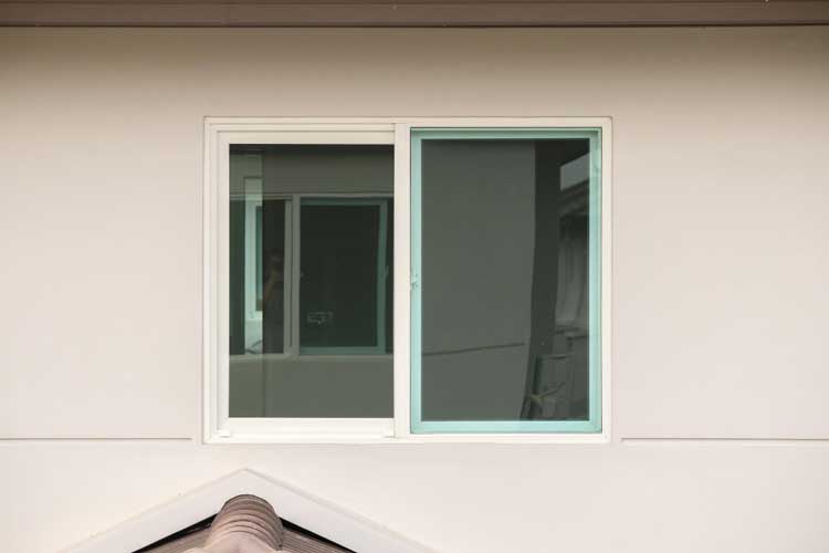 Home exterior featuring a white-framed sliding window with one panel open, showcasing clean modern design, smooth functionality, and professionally installed Sliding Windows Atlanta for ventilation and energy efficiency.