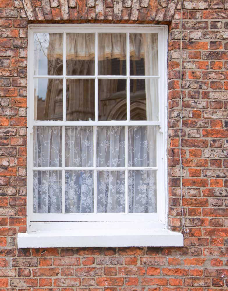 Couple sitting at a table by a large white-framed window enjoying coffee and conversation in a bright modern interior, highlighting natural light, comfort, and professional Window Replacement Atlanta services for stylish, energy-efficient spaces.
